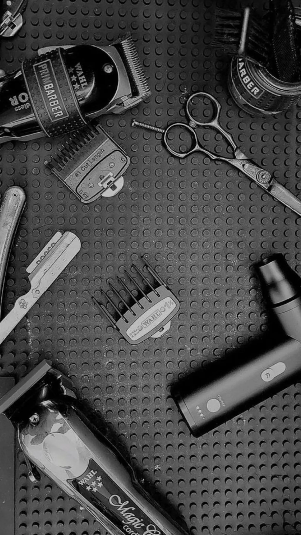 Herramientas de barbería sobre una superficie negra, incluyendo una máquina de cortar cabello, tijeras, peines y un cortapelos, ideales para estilistas y barberos.